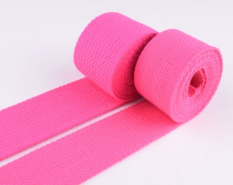 May include: Two rolls of pink webbing, a type of flat, woven fabric often used for straps and handles.