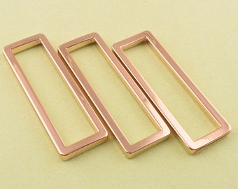 Puede incluir: Tres marcos rectangulares de metal de color dorado. Los marcos son huecos y tienen un acabado liso y pulido.