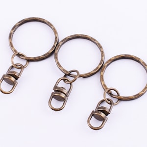 Puede incluir: Tres llaveros de oro antiguo con cierres giratorios. Cada anillo tiene un acabado martillado.