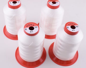 Può includere: Quattro bobine di filo bianco con etichette rosse e bianche. Le etichette hanno testo cinese e i numeri 200, 30#, 60#, e 1200Y, 2000Y. Le bobine sono su una superficie bianca.
