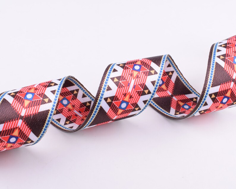May include: A brown, white, red, and blue patterned ribbon with a geometric design. The ribbon is woven and has a textured surface.