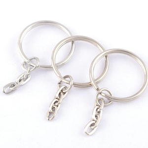 Puede incluir: Tres llaveros plateados con anillos unidos y cadenas de conexión.