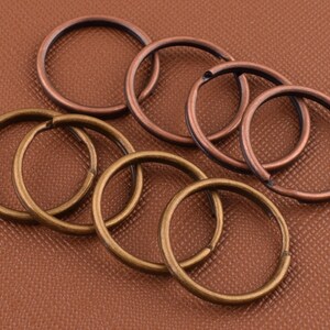 Può includere: Un set di otto portachiavi in metallo in due diverse finiture: rame e ottone. Gli anelli sono disposti in cerchio, con gli anelli di rame all'esterno e gli anelli di ottone all'interno.