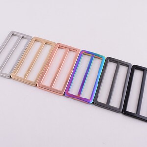 May include: A set of six metal slider buckles in different finishes, including silver, gold, rose gold, rainbow, black, and gunmetal.