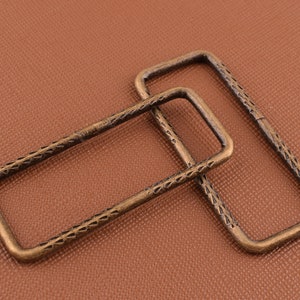 May include: Two antique gold-toned metal belt buckle frames with a decorative etched pattern.