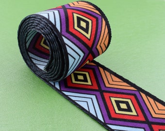 May include: A colorful woven ribbon with a geometric pattern of diamonds and stripes in shades of orange, yellow, purple, blue, and black.