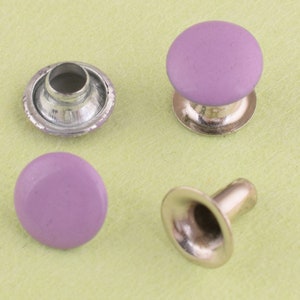 Puede incluir: Cuatro botones a presión de metal plateado con tapas de plástico morado. Los botones a presión se utilizan para unir tela o cuero.