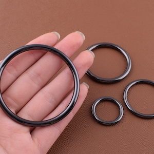 K&ouml;nnte beinhalten: Vier schwarze Metallringe in verschiedenen Gr&ouml;&szlig;en. Die Ringe sind glatt und haben eine gl&auml;nzende Oberfl&auml;che.