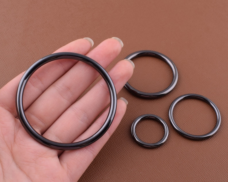 K&ouml;nnte beinhalten: Vier schwarze Metallringe in verschiedenen Gr&ouml;&szlig;en. Die Ringe sind glatt und haben eine gl&auml;nzende Oberfl&auml;che.