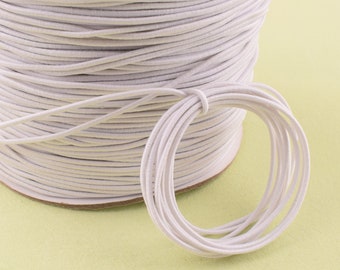 May include: A spool of white elastic cord, wound tightly and ready to be used for crafting projects.