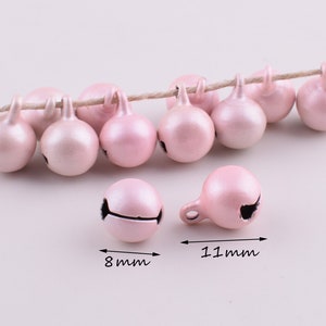 Peut inclure: Une cha&icirc;ne de 11 mm de clochettes de No&euml;l en m&eacute;tal rose avec une finition brillante. Les clochettes sont enfil&eacute;es sur une ficelle de ficelle naturelle.