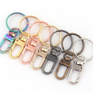 Peut inclure: Ensemble de six porte-clés avec différentes finitions métalliques colorées. Les porte-clés sont dotés d'un anneau rond et d'un mousqueton pivotant. Les couleurs comprennent l'arc-en-ciel, l'or rose, l'or, l'argent, le laiton antique et le noir.