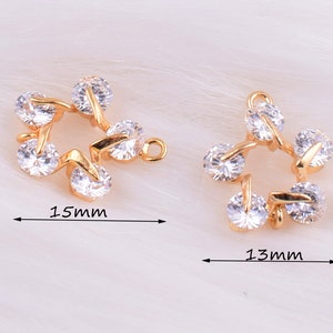 May include: Two gold-tone star-shaped charms with clear crystal accents. The larger charm measures 1.5 inches and the smaller charm measures 1.3 inches.