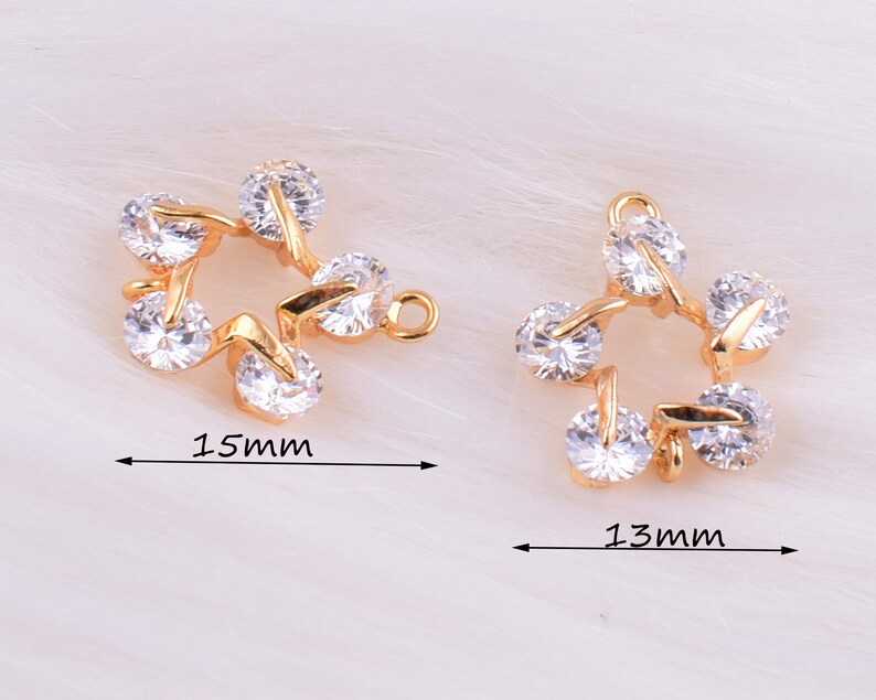 May include: Two gold-tone star-shaped charms with clear crystal accents. The larger charm measures 1.5 inches and the smaller charm measures 1.3 inches.