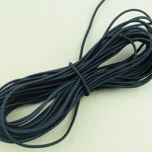 May include: A spool of dark gray elastic cord. The cord is wound tightly and is ready to be used for crafting or sewing projects.