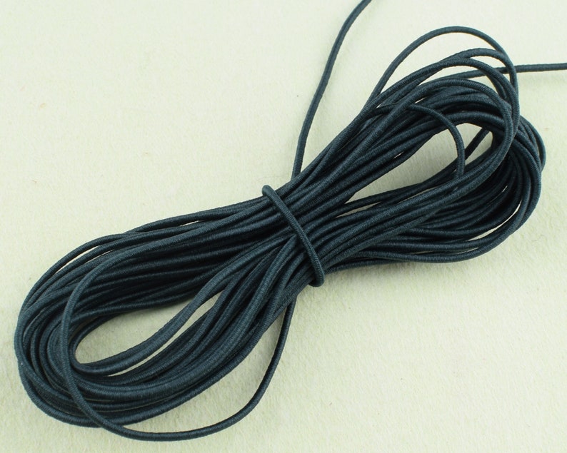 May include: A spool of dark gray elastic cord. The cord is wound tightly and is ready to be used for crafting or sewing projects.