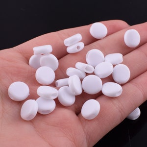 May include: A collection of white plastic ear savers for face masks. The ear savers are small and round, with a hole in the center for attaching to a mask.