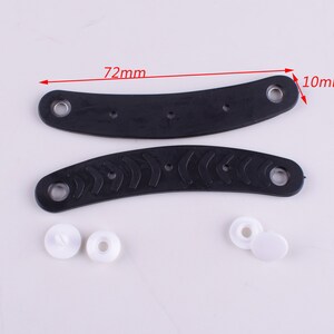Puede incluir: Dos asas de pl&aacute;stico negro con una superficie texturizada y dos broches de pl&aacute;stico blanco. Las asas miden 72 mm de largo y 10 mm de ancho.