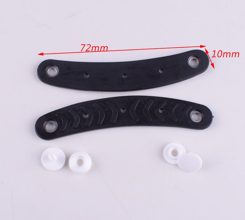 Puede incluir: Dos asas de pl&aacute;stico negro con una superficie texturizada y dos broches de pl&aacute;stico blanco. Las asas miden 72 mm de largo y 10 mm de ancho.