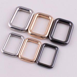May include: Five metal D-rings in different sizes. The rings are silver, gold, and black.