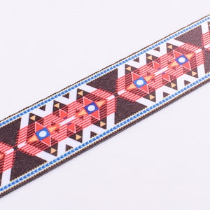 May include: Brown, red, white, and blue patterned ribbon with a geometric design. The ribbon has a woven texture.