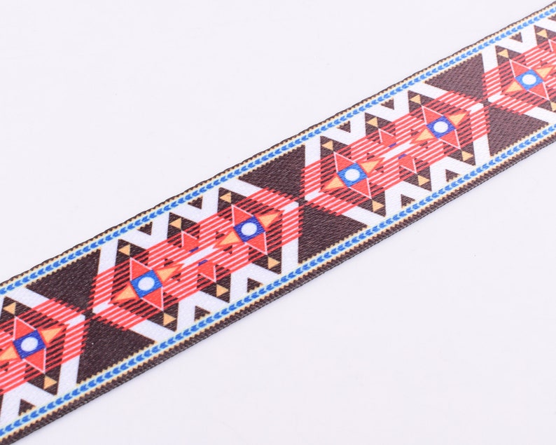 May include: Brown, red, white, and blue patterned ribbon with a geometric design. The ribbon has a woven texture.