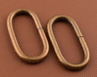 May include: Two oval-shaped metal rings with a brass finish. The rings are smooth and have a slightly rounded edge.