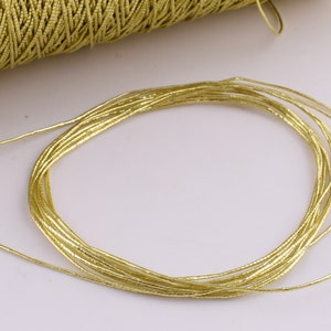 May include: A close-up of a gold metallic cord, made of many thin strands of wire, coiled into a circle.