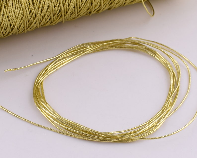 May include: A close-up of a gold metallic cord, made of many thin strands of wire, coiled into a circle.