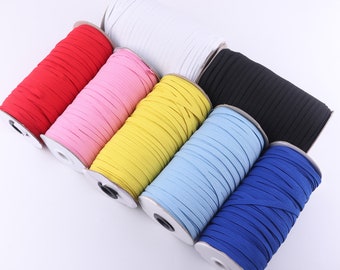 May include: Six spools of elastic cord in various colours, including red, pink, yellow, light blue, dark blue, and black. The spools are arranged in a semi-circle on a white surface.