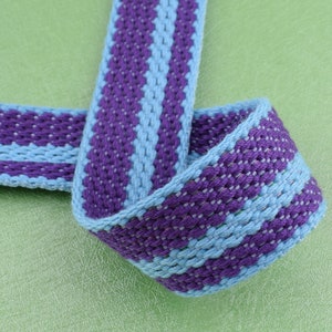 May include: Purple and light blue striped woven ribbon with a textured surface.
