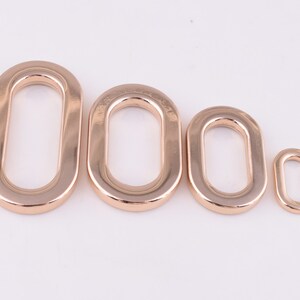 May include: Three gold-colored metal oval rings of different sizes. The rings are smooth and have a polished finish.