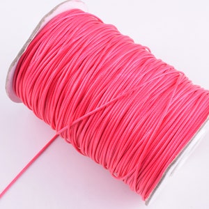 Puede incluir: Un carrete de cordón encerado de color rosa brillante, perfecto para la elaboración de joyas o proyectos de manualidades.