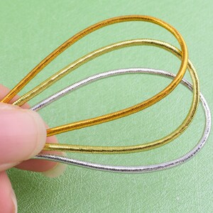 May include: Three gold and silver chain necklaces layered together. The necklaces are made of thin, flexible metal and are a popular accessory for women.