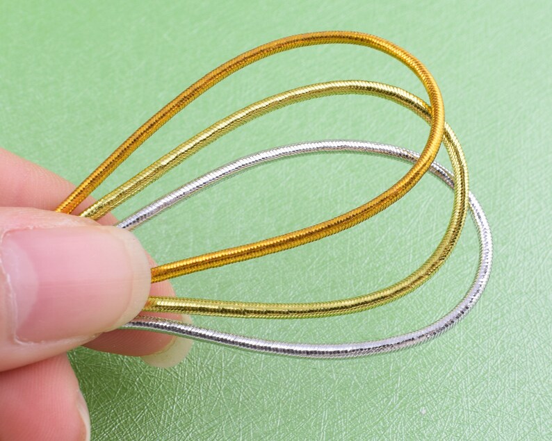 May include: Three gold and silver chain necklaces layered together. The necklaces are made of thin, flexible metal and are a popular accessory for women.