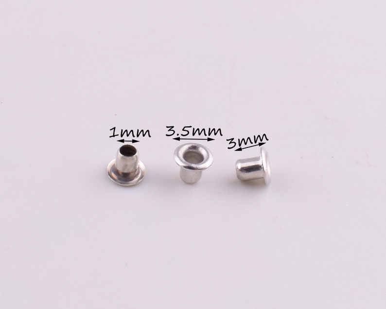 May include: Three silver eyelets with different sizes: 1 mm, 3.5 mm, and 3 mm. The eyelets are on a white background.