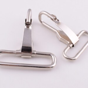 May include: Two silver metal swivel hooks with a D-ring on one end and a hook on the other end.