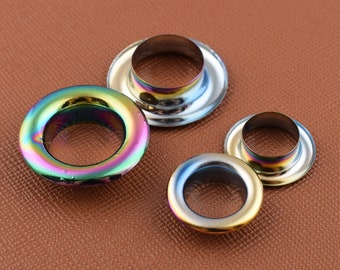 Op de afbeelding: Vier metalen oogjes in verschillende maten. De oogjes zijn zilver, goud en regenboogkleurig.