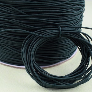 May include: A spool of dark green elastic cord. The cord is wound tightly around the spool and is ready to be used for crafting projects.