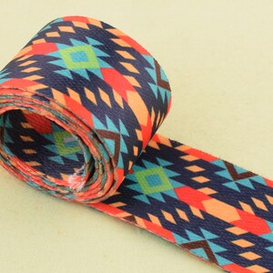May include: A rolled up colorful patterned webbing strap with a geometric design in shades of blue, orange, red, and brown.