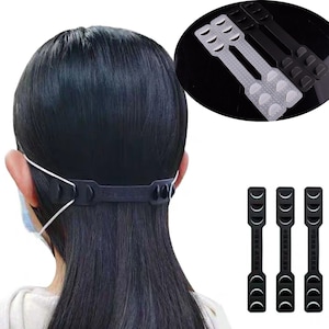 Może przedstawiać: Zestaw trzech czarnych plastikowych przedłużaczy do masek na twarz z regulowanymi paskami. Przedłużacze zostały zaprojektowane, aby pomóc zmniejszyć ból uszu spowodowany noszeniem maski na twarz przez dłuższy czas.