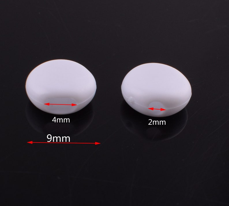 May include: Two white plastic beads, one measuring 9mm in diameter and 4mm in height, and the other measuring 2mm in height.