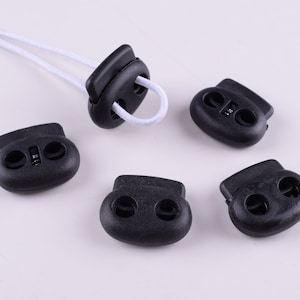 Puede incluir: Cinco cierres de cordón de plástico negro, cada uno con dos agujeros. Los cierres de cordón están diseñados para asegurar cordones o correas.