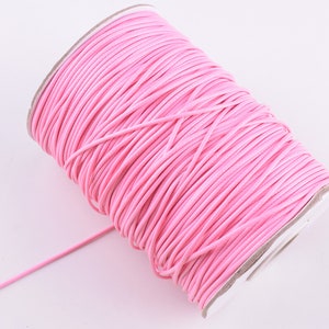 Könnte beinhalten: Eine Spule mit rosa gewachstem Kordel, eine Art Schnur, die für die Schmuckherstellung und das Basteln verwendet wird.