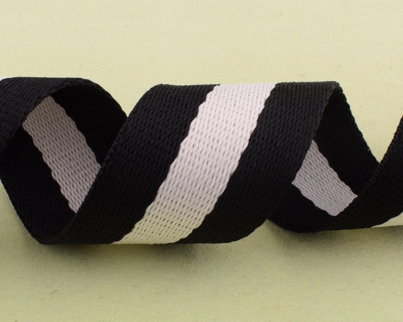 May include: Black and white striped webbing ribbon. The ribbon is woven with a textured pattern.