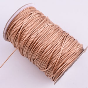 May include: A spool of light brown waxed cord, perfect for jewelry making, macrame, or crafts.