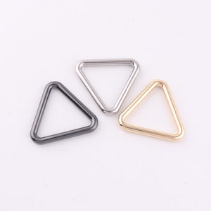 May include: Three triangle-shaped metal rings in silver, black, and gold.