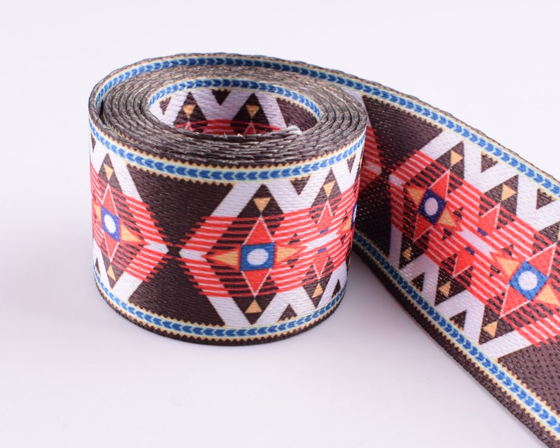 May include: A brown, white, red, and blue patterned webbing with a geometric design. The webbing is rolled up and ready to be used for crafting projects.