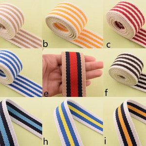 May include: Nine rolls of striped cotton webbing in various colors, including red, white, blue, yellow, black, and brown. The webbing is approximately 2.5 cm wide.