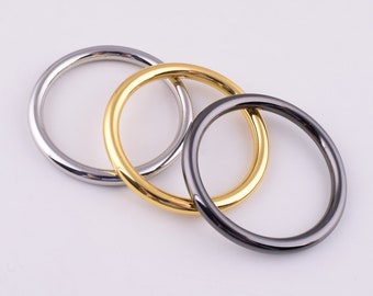 May include: Three metal rings in silver, gold, and gunmetal gray. The rings are circular and have a smooth, shiny finish. The rings are overlapping each other, with the gold ring in the center.